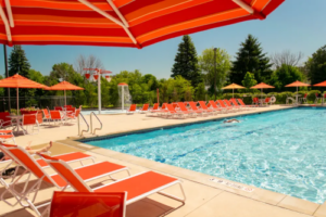 A vibrant pool scene featuring orange and white umbrellas alongside comfortable chairs, inviting relaxation and leisure.