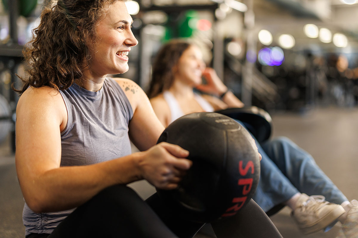 Woman works out on the ground with medicine ball in a fitness center