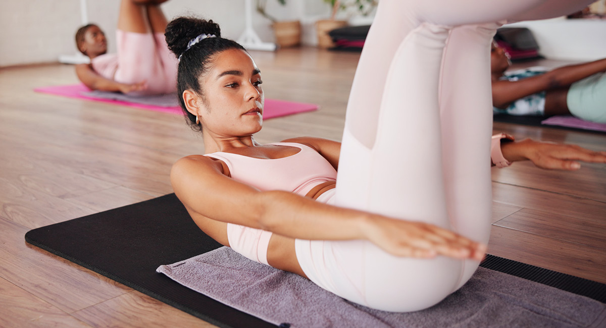 Woman does Pilates on mat with a group of people