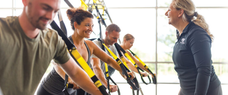 Trainer works with a team of clients using TRX resistance straps