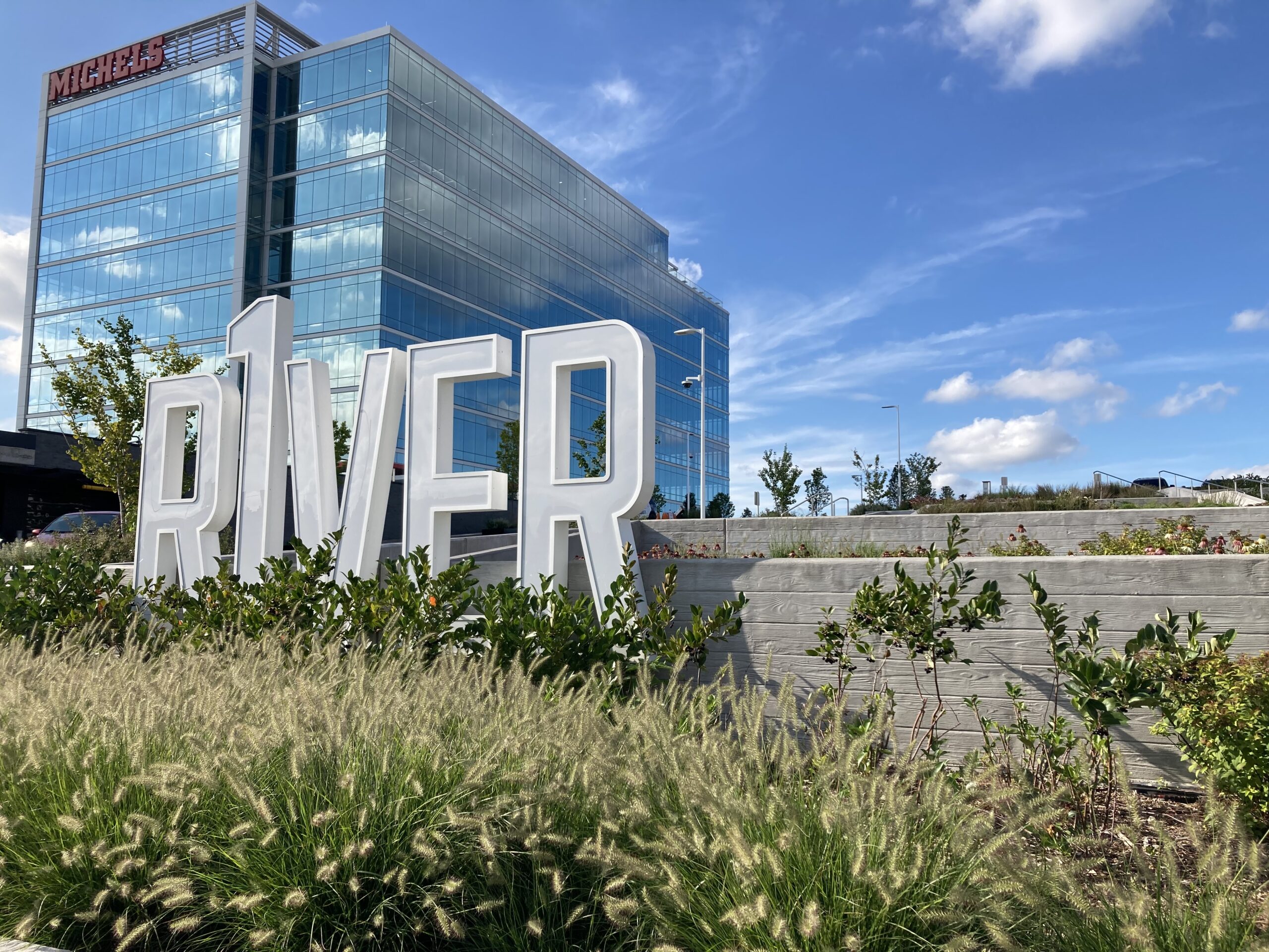 R1VER sign in front of an urban glass apartment building