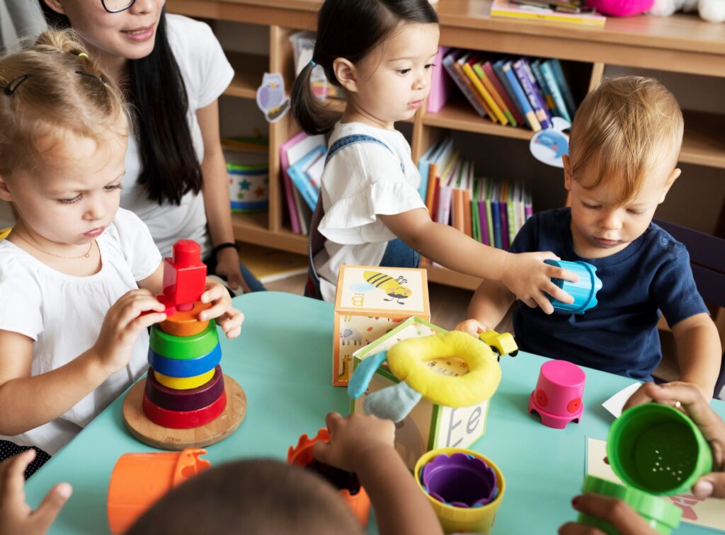 Nursery children playing with teacher in the class